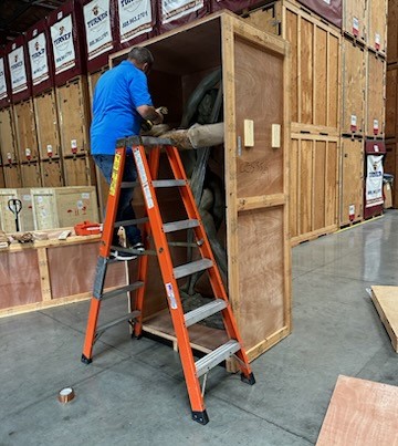 Turner Moving & Storage employee standing on a ladder, building a custom crate