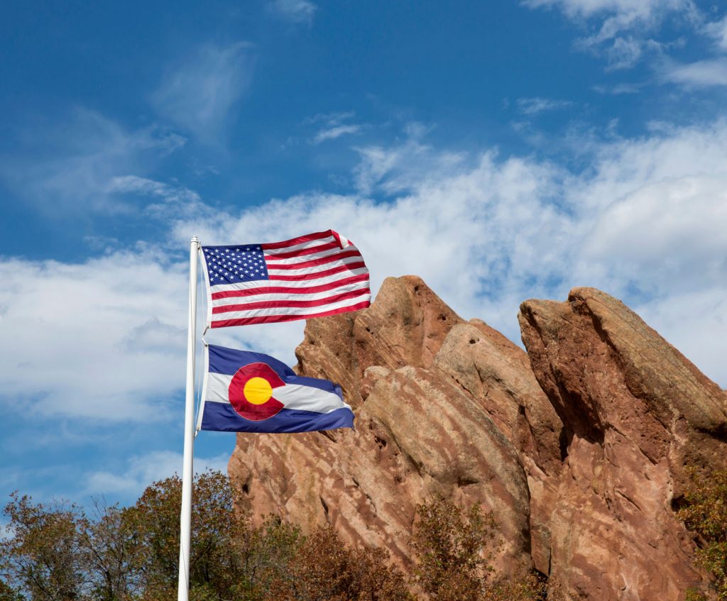 US flag in front of red rock formation at Roxborough State Park in Colorado